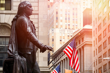 Wall Street in New York City at sunset with the statue of George Washington at the Federal Hall