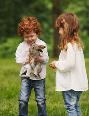 boy and girl playing with rabbit in park