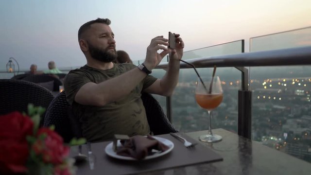 Man sitting in skybar and doing photos of the view 
