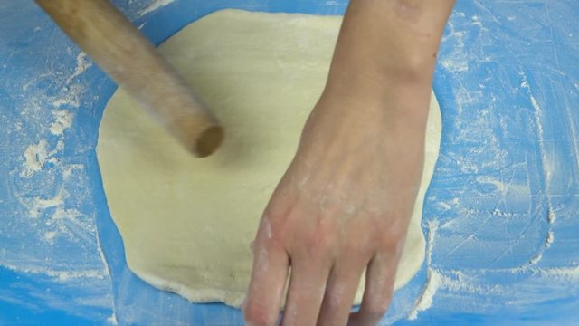 Slow motion footage. Baker hand kneading and flipping dough with rolling pin