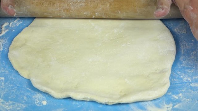 Slow motion footage. Baker hand kneading dough with rolling pin