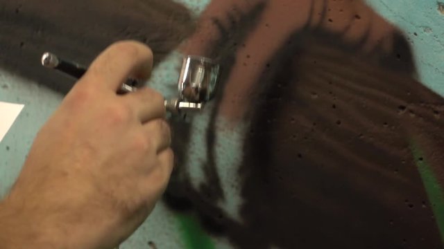 Slow-mo footage. Artist hand airbrush painting. Close-up