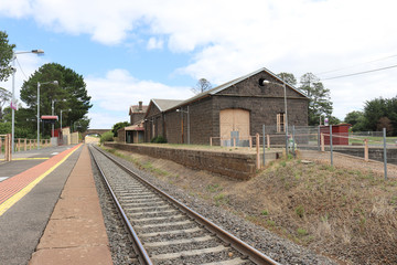 Fototapeta na wymiar train tracks and a bluestone railway station building and platform