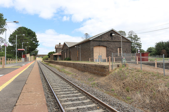 train tracks and a bluestone railway station building and platform