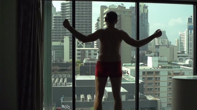 Man wearing underwear and stretching muscles in fron of the mirror, slow motion shot at 120fps
