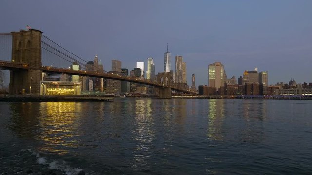 Brooklin Bridge at dawn next to the East River in New York City.