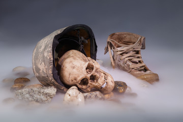 Corpses in military uniform on ice smoke. The human skull is next to the military cap and boots.