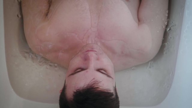 Overhead View Of Young Athlete Wincing During An Ice Bath After Working Out SLOW MOTION