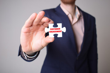Businessman holding a puzzle with the inscription:CUSTOMER ENGAGEMENT