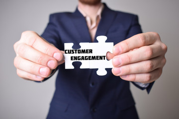 Businessman holding a puzzle with the inscription:CUSTOMER ENGAGEMENT