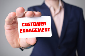 Businessman shows business card with the inscription:CUSTOMER ENGAGEMENT