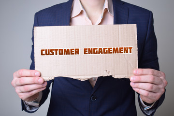 A businessman holds a cardboard with an inscription:CUSTOMER ENGAGEMENT