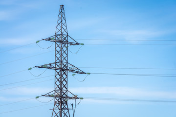 Iron tower with electric wires energized against the background of the blue sky.