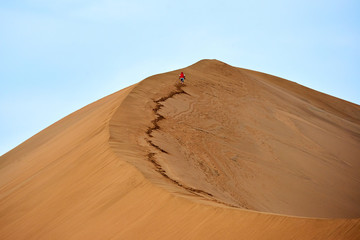 Fototapeta na wymiar sand-dune and the lonely traveler. In physical geography, a dune is a hill of loose sand.