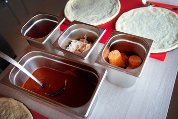 Products for pizza with pepperoni sausage and sauce on the table top view.The process of cooking pizza.