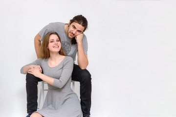 beautiful and young man and woman are sitting on a chair and on the floor in different poses