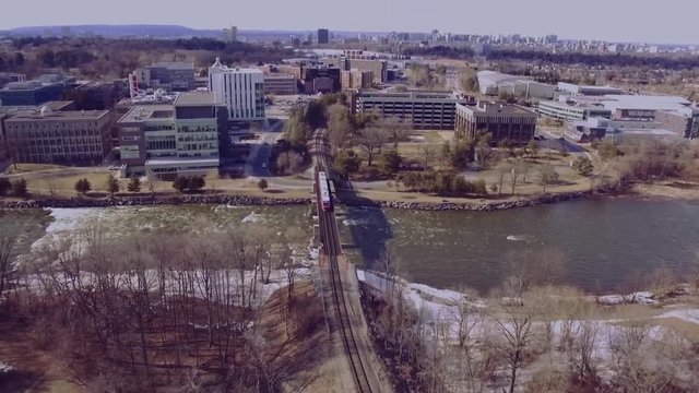Aerial tracking shot of a train going over a river into a forest.