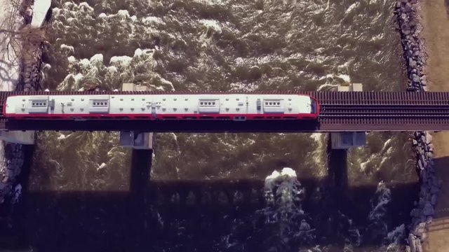 Aerial shot of a train going over the river.