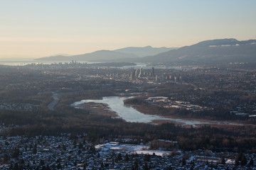 Aerial view of Burnaby Lake and the city in the background during a vibrant sunset. Taken in Greater Vancouver, British Columbia, Canada.