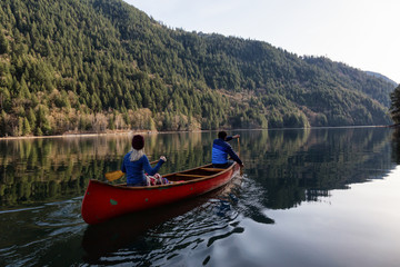 Couple friends canoeing on a wooden canoe during a sunny day. Taken in Harrison River, East of Vancouver, British Columbia, Canada.