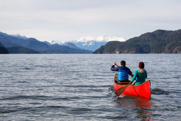 Naklejka premium Couple friends canoeing on a wooden canoe during a sunny day. Taken in Harrison Lake, East of Vancouver, British Columbia, Canada.