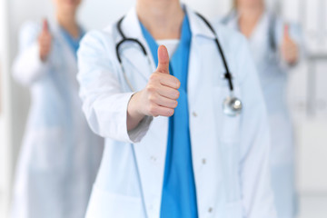 Groupe of medicine doctors show OK sign with thumb up close up. Success and high level service in health care, best treatment and customer loyalty and physical concept. Copy space for advertisement