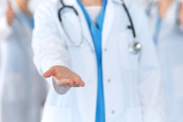 Group of medicine doctors offering helping hand  for shaking hand or saving life closeup. Partnership and trust concept in health care or medical cure 