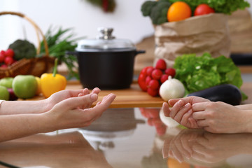 Closeup of human hands cooking in kitchen. Women discuss a menu. Healthy meal, vegetarian food and lifestyle concepts