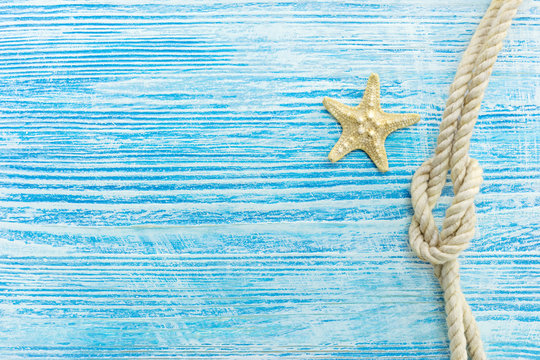 starfish and marine knot on weathered blue wooden surface. summer holiday background