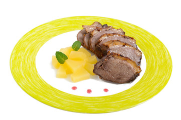 Duck breast Magret with pieces of pineapple on a plate isolated on white background. French traditional meat dish. Christmas menu. Festive kitchen.