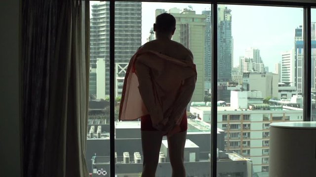 Man undresses himself in front of the window, slow motion shot at 240fps
