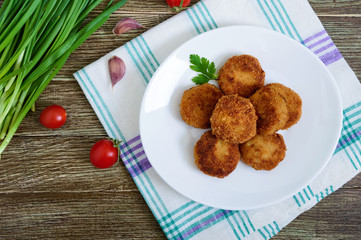 Cutlets. Juicy, golden fried cutlets in a ceramic plate on a wooden table. Top view