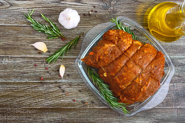 A large piece of pork meat on a wooden table, marinated in spices, stuffed with garlic and carrots, ready for baking. Preparation of a festive meat dish.