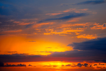 Cloudy sky and bright sun rise over the horizon.