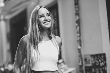 Beautiful young blonde woman smiling in urban background.