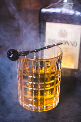 A glass with an alcoholic beverage in the smoke. - 200615315