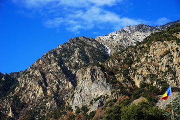 Flag of the Principality of Andorra against the background of the Pyrenees mountains.