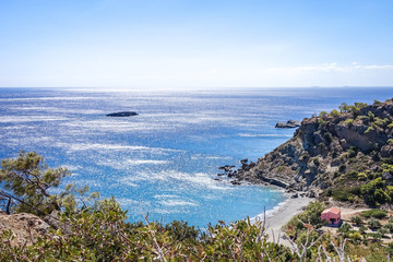 a view from the mountains to the blue Mediterranean, the sun plays in sea water, the coast has a small sandy beach