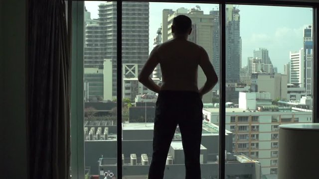 Man puts pants on while standing in front of the window, slow motion shot at 120fps
