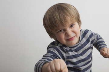 Niño (5 años) desafiante con un puño de la mano delante y otro detrás.