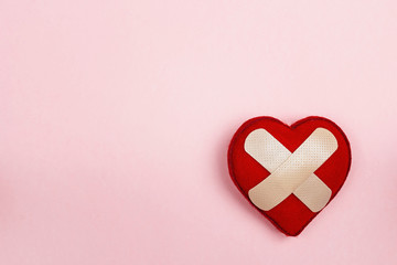 Heart with adhesive plaster on pink background. Copy space.