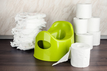 children's toilet pot green, nappies and toilet paper, the concept of the baby's transition from...