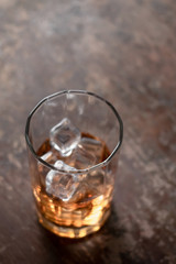 Glass of whiskey with ice on black background