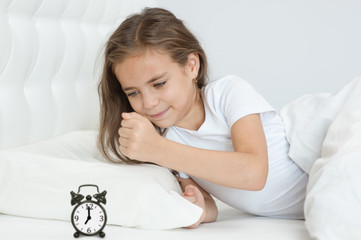 Naklejka premium little angry girl wants to break the alarm clock with her fist