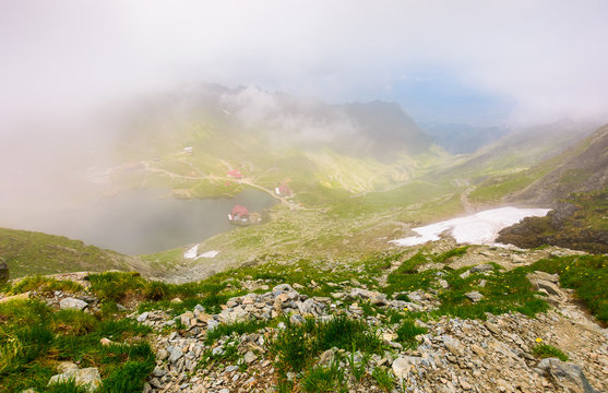 Balea lake in fog view from the top. lovely summer landscape with low clouds around