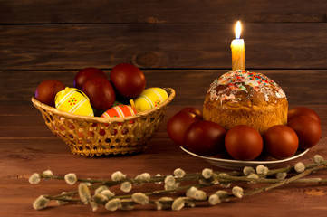 Easter cake, Easter eggs and a lighted candle on a wooden table.