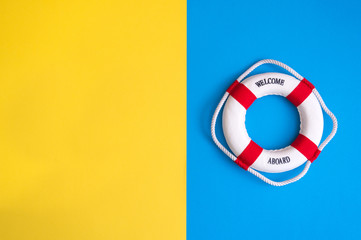 Lifebuoy on a yellow and blue background with blank space for text. Top view travel or vacation...