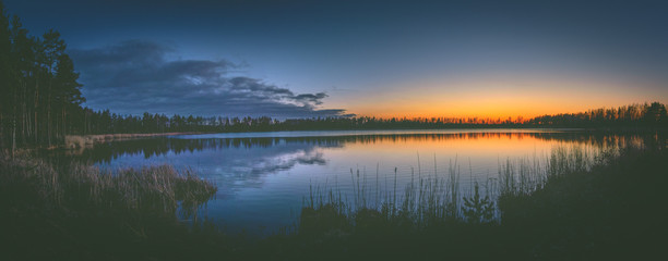Colorful sunset over the lake in late evening in Spring. Peaceful scenery with clear sky and reflections in water.