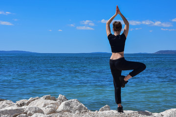 Young healthy woman practicing yoga on the beach at sunrise