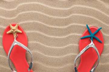 Pink flip flops and starfish on the sand of the beach. Concept of rest.